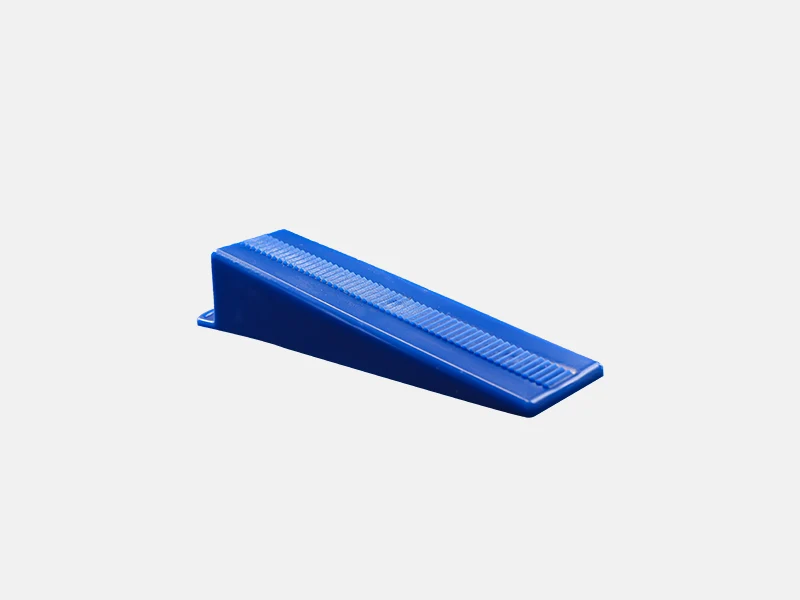 A bright blue tile leveling wedge lying flat, with a serrated design, prominently displayed against a solid black background for a striking visual contrast.